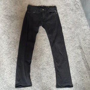 Replay Hyperflex svarta jeans - Storlek 31, 32  Svarta Replay Hyperflex jeans med slim passform och klassisk femficksdesign. Stretchigt material som sitter snyggt och bekvämt, perfekt för dig som gillar en modern och stilren look. Diskreta Replay-loggor vid fickan och insidan av linningen.