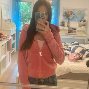 Juicy Couture rosa velour hoodie - Säljer en ikonisk rosa hoodie från Juicy Couture i mjuk velour med glittrande Juicy-text på ryggen. Tröjan har huva med snörning, dragkedja med J logga och en stor ficka fram. Perfekt för dig som gillar Y2K-stilen och vill ha något extra comfy. Pris går att diskutera.