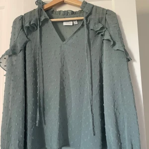 Grön blus med volanger - Jättesnygg volangblus från VILA. Använd endast ett fåtal gånger då jag inte tycker den passar på just mig.💞