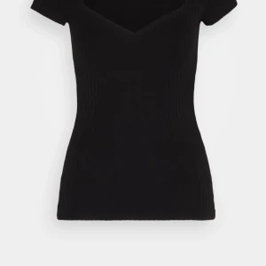 Svart ribbad v-ringad topp - Snygg svart ribbad topp med v-ringad hals och korta ärmar. Den har en slim passform och är perfekt för att skapa en clean och stilren look. Materialet är mjukt och stretchigt för extra komfort.
