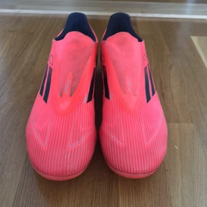 Adidas F50 rosa fotbollsskor - Säljer ett par grymma Adidas F50 fotbollsskor i en riktigt snygg rosa färg med svarta detaljer och silvriga loggor. Skorna har låg profil, platt sula med dobbar och är tillverkade i syntetmaterial för lätt känsla på planen.