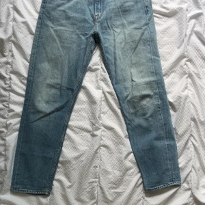 Ljusblå raka jeans från Tiger of sweden  - Säljer ett par ljusblå jeans från tiger of sweden som har en snygg skinnpatch bak i midjan. Jeansen har raka ben och en avslappnad passform, perfekt till vardagslooken. Tillverkade i mjukt denimtyg för en bekväm känsla.