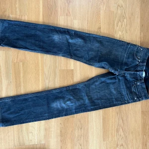 Gråa lågmidjade jeans från Filippa K W30 L34 - Snygga mörkgråa lågmidjade jeans från Filippa K i klassisk rak modell. Jeansen är tillverkade i 100% bomull och har fem fickor, bälteshällor och dragkedja. Perfekta för dig som gillar stilrena och tidlösa jeans med en clean look. Från mans avdelningen men använts endast av tjejer så funkar super för båda.