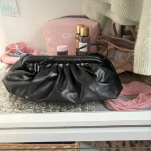 Svart clutch väska - Säljer en lite större svart clutch väska. Väskan har en enkel axelrem och rymligt fack, perfekt för att bära med det viktigaste. Såå fin!! 