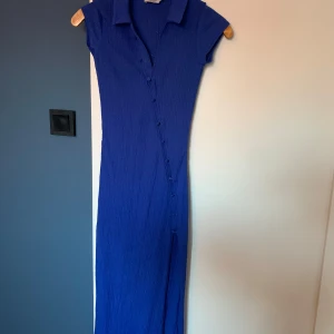 Blå långklänning Melissa Bentzen x NA-KD - Supersnygg blå långklänning med krage och korta ärmar från Melissa Bentzen x NA-KD. Klänningen har en figurnära passform knappar längs framsidan💙💙