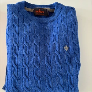 Blå kabelstickad tröja från Morris - Snygg blå kabelstickad tröja från Morris i 100% merinoull. Klassisk rund halsringning och diskret broderad logga på bröstet. Perfekt för dig som gillar stilrena och tidlösa plagg med en modern touch. Dyr i inköp. Stl XS men passar barn stl 150