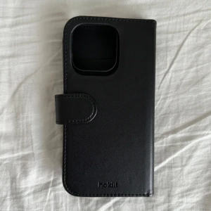 Holdit plånboksfodral mobilskal iPhone 15 Pro - Snyggt läderfodral med inbyggda kortfack till iPhone 15 Pro från Holdit. Skalet fästs i fodralet med magneter så att du enkelt kan ta ut det när du inte är i behov av hela plånboksfodralet. Helt ny, aldrig använd! Nypris 300 kr 