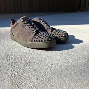 Christian Louboutin sneakers med nitar - Gråa skor från Christian Louboutin | skick 7,5/10 | Lite defekter ( se bild 3 och 4 ) | har ingen box bara skorna | storlek 43 | fråga så kan jag ge mer bilder | priset kan diskuteras 