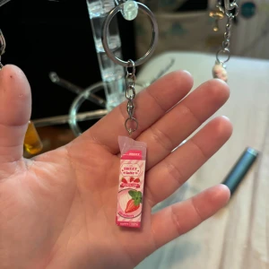 Söt rosa jordgubbsmjölk nyckelring - Supergullig nyckelring formad som en jordgubbsmjölk-kartong med texten 'Sweet Latte Strawberry'. Väskan är rosa med vita och röda detaljer och har en unik, lekfull design som verkligen sticker ut. Perfekt för dig som gillar kawaii-stil och vill ha något annorlunda.