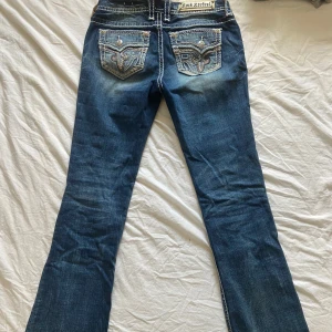 Bootcut Rock revival jeans  - Snygga bootcut jeans från rock revival! Lowwaist/ midwaist. Supersnygga fickor och detaljer💕Kommer tyvärr inte till användning längre så de inte riktigt passar mig💔 storlek 29, midjemått-38cm. Innerbenslängd- 77cm💕 