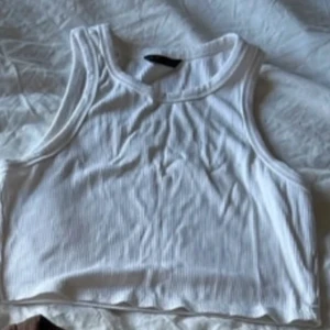 2-pack croppade ribbade linnen - Säljer två croppade linnen i ribbad bomull, ett vitt och ett svart. Båda har breda axelband och rund halsringning, perfekta till jeans eller kjol. Snygg basic-stil som funkar året runt och är superenkla att matcha.