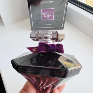 Lancôme La Nuit Trésor Parfym - Säljer en lyxig parfym från Lancôme, La Nuit Trésor. Flaskan är diamantformad i lila och svart glas med en elegant lila sammetsrosett vid halsen. Doften är sensuell och flaskan är riktigt snygg att ha framme på hyllan. Endast testad för lukt. Har orderbekräftelse.