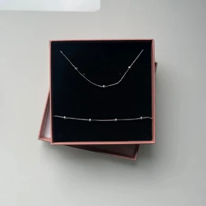 Matchande armband/halsband - Säljer ett stilrent set från Edblad med ett tunt halsband och matchande armband i silverfärgad metall. Båda smyckena har små, diskreta kulor längs kedjan som ger en minimalistisk och modern känsla. Perfekt för dig som gillar enkel och snygg design. Hör av dig vid frågor