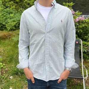 Ralph Lauren skjorta - Säljer en stilren och snygg blåvit randig Ralph Lauren-skjorta. Modellen är M, slim fit  Skjortan är i mycket fint skick och perfekt nu till sommaren.  Har du några frågor? Tveka inte att höra av dig! Allt gott från Deluxe-garderoben.