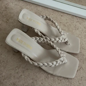 Beige sandaler med flätad rem och klack - Sandaler i beige med fyrkantig tå, flätad rem och transparent klack. Snyggt minimalistiska med plattformsinspirerad känsla och öppen tå. 