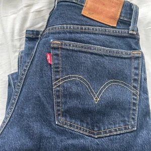 Levi's 501 Premium mörkblå jeans - Klassiska Levi's 501 Premium jeans i mörkblå tvätt. Högmidjade med rak passform och snygga kontrastsömmar. Ikonisk röd Levi's-tag på bakfickan och läderpatch i midjan. Tillverkade i slitstarkt jeanstyg av bomull.