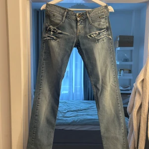 Ljusblå slitna lågmidjade jeans från Fornarina - Säljer ett par ljusblå jeans från Fornarina med snygga slitningar och rivna detaljer framtill. Jeansen har raka ben, klassiska fickor och coola kontrastsömmar på bakfickorna. Perfekt för dig som gillar en vintage och cool look. Lågmidjadejeans / jeans med hål. Hör gärna av er vid frågor 🙌🙌