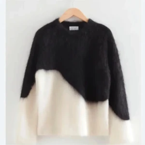 Svartvit stickad tröja - Säljer en supermjuk och fluffig stickad tröja i svart och vitt. Tröjan har en cool asymmetrisk färgblock-design och långa ärmar. Perfekt för dig som vill ha en mysig men ändå trendig look under kyliga dagar.