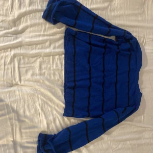 Blå randig stickad tröja Urban Heritage - Säljer en blå stickad tröja från Urban Heritage med svarta ränder. Tröjan har lång ärm och en klassisk rund halsringning. Den är också bredare vid händerna 