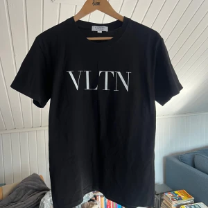 Valentino tshirt  - Snygg svart t-shirt från Valentino med stor vit VLTN-logga på bröstet. Klassisk rund halsringning och korta ärmar. Tillverkad i mjuk bomull för en skön känsla och stilren look. Perfekt inför sommaren och tshirt väder.