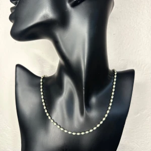 Retro halsband i silvrig metall – grönskiftande vintagefinish - Vintageinspirerat halsband med små ovala metallpärlor i silvrig finish. Den subtila gröna tonen ger ett elegant, åldrat uttryck. Ca 40 cm långt + 5,5 cm förlängning, pärlorna mäter ca 3 mm. Lätt att bära, passar både till vardag och fest. Material: metallpärlor med silvrig yta, hittar inga Silverstämplar, säljs därför inte som silver. Prutar inte men jag erbjuder bundlerabatt. Rensar smyckesskrin – kika gärna på mina andra annonser också! 