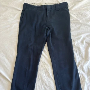 Mörkblå slim fit cargopants från Dickies - Säljer ett par mörkblå cargopants från Dickies i slim fit-modell. Byxorna har stora fickor på sidorna, bälteshällor och raka ben. Perfekta för dig som gillar streetwear och funktionella detaljer.