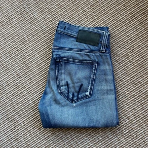 Blå bootcut jeans från Fornarina - Snygga blå jeans från Fornarina med bootcut-modell och slitna detaljer. Jeansen har klassisk femficksdesign, broderade bakfickor och tydliga slitningar framtill. Storlek 25. Mycket välvårdade.