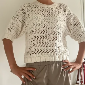 Vit stickad tröja med hålmönster - Säljer en vit stickad tröja med snyggt hålmönster och ribbade muddar. Tröjan har en avslappnad passform och trekvartsärmar, perfekt för lager-på-lager och chill stil. Passar lika bra till jeans som till kjol. 