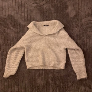 Ljusgrå stickad tröja med krage - Supermysig ljusgrå stickad tröja från hm med bred krage och v-ringning. Tröjan har en croppad passform och långa ärmar, perfekt att matcha med jeans eller kjol!💕