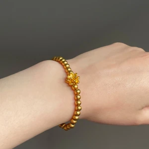 Guldfärgat pärlarmband med blomma - Stilrent armband med små guldfärgade pärlor och en söt blomdetalj i mitten. Armbandet har en enkel och elegant design som passar perfekt för dig som gillar att sticka ut med detaljer. Elastiskt band gör det lätt att ta på och av. Nyskick.