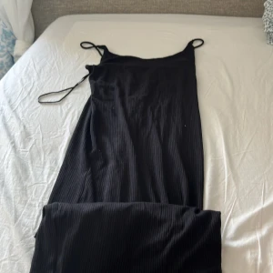 Svart ribbad långklänning H&M XS - Svart ribbad långklänning från H&M med tunna axelband. Enkel och stilren modell som sitter snyggt på kroppen. Perfekt för dig som gillar minimalistisk stil och vill ha en klänning som funkar till många tillfällen.