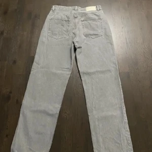 Grå baggy jeansbyxor - Säljer ett par grå jeansbyxor med raka ben och klassiska bakfickor. Byxorna har en enkel och clean look, perfekta för dig som gillar en avslappnad stil. Passar till det mesta och är lätta att matcha med olika outfits.