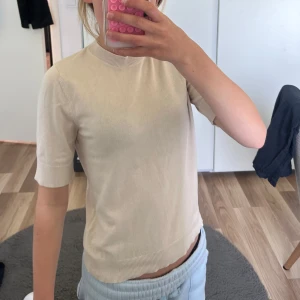 Beige stickad tröja från Lager 157 XS - Snygg beige stickad tröja från Lager 157 i storlek XS. Tröjan har korta ärmar, rund halsringning och ribbade muddar vid ärmslut och nederkant. Perfekt för dig som gillar en clean och enkel stil med en mjuk känsla.