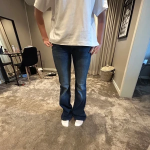 Blå bootcut jeans  - Säljer ett par klassiska blå jeans med bootcut-snitt och lowwaist. Jeansen har en snygg tvätt och sitter tajt över låren men släpper ut vid vaden. Nypris 600 kr, finns ej att köpa längre! Storlek 28x36 långa på mig som är 174!