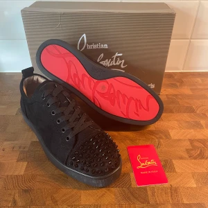 Christian Louboutins med spikar - Hej 👋🏽 Säljer ett par nya svarta sneakers från Christian Louboutin i mocka med röd sula och svarta spikar. Lådan har lite skador men skorna är som dem ska vara. Storlek 41 och skriv gärna om ni har frågor!