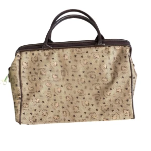 Hello Kitty beige handväska - Söt beige handväska med Hello Kitty-mönster och bruna detaljer. Väskan har två handtag, dragkedja upptill och rymligt fack inuti. 