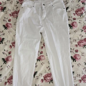 Vita raka jeansbyxor i bomull - Snygga vita jeansbyxor med rak passform och klassisk design. Byxorna har hög midja och är tillverkade i mjuk bomull, perfekta för en fräsch och clean look. Passar till allt och är lätta att styla med olika outfits.