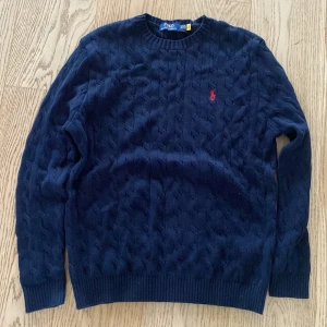 Mörkblå kabelstickad tröja Polo Ralph Lauren - Säljer en mörkblå kabelstickad tröja från Polo Ralph Lauren med klassisk röd broderad logga på bröstet. Tröjan har rund halsringning, långa ärmar och ribbade muddar. Andväts ungefär 2 gånger. Det är bara att skriva om du har några frågor! Pris kan diskuteras vid snabb affär 