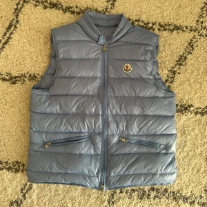 Baby blue dunväst från Moncler - Snygg baby blue dunväst från Moncler med klassisk logga på bröstet. Västen har två dragkedjefickor framtill och stängs med dragkedja. Den är quiltad och har en hög krage för extra stilpoäng. Tags följer med. Storleken är L men passar även M. Skambud besvaras inte. Fraktar samma dag vid köp innan 20:00.