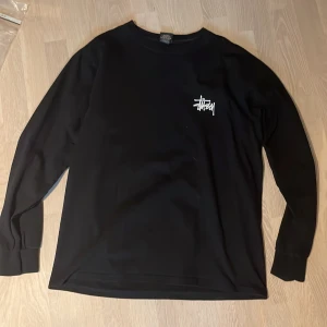 Svart Stüssy tröja M - En svart långarmad tshirt från stussy som jag köpt från stussy.eu för ett tag sen. Har använt tröjan ungefär tre gånger och den är perfekt för dig som gillar streetwear och är i nyskick.