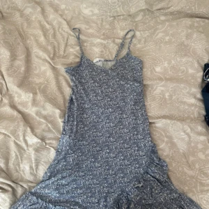 Blå blommig sommarklänning med volang - Supersöt blå klänning med små vita blommor, smala axelband och volangkant nertill. Perfekt för varma dagar och har en lätt, flowy känsla. Sitter snyggt och är riktigt bekväm att bära.