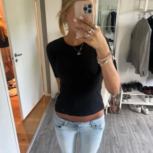 Svart ribbad topp ❣️ - En svart ribbad topp  med korta ärmar och lätt puff vid axlarna. Modellen är figurnära och har rund halsringning. Perfekt att styla med jeans eller kjol för en clean look.