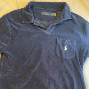 Mörkblå pikétröja från Polo Ralph Lauren - Snygg mörkblå pikétröja från Polo Ralph Lauren i frotté .  Tröjan är använd ändast en gång sen har den bara legat i engarderob