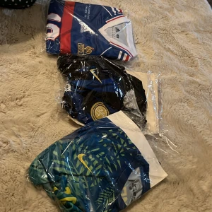 Tre fotbollströjor Adidas & Nike - Tre snygga fotbollströjor: en blå, vit och röd Adidas-tröja från Frankrike 98, en blå och svart Inter-tröja från Nike med klubbmärke, samt en blågrön Nike-tröja med grafiskt mönster och gula detaljer. Perfekta för dig som älskar fotboll och vill sticka ut på planen.