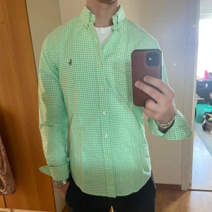 Grön- vit rutig skjorta från Ralph Lauren strl S - Sjukt fet Raffe skjorta till sommaren samt en stilren outfit. Skick 9/10. Endast en liten fläck på vänster arm. Passar en som är emellan 170-180 cm lång. Hör av er vid intresse! 
