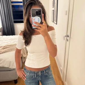 Vit offshoulder topp från H&M - Säljer en vit offshoulder topp från H&M i storlek XS. Toppens passform är slim och den är croppad med korta ärmar. Perfekt till jeans eller kjol för en clean och fräsch look. Gjord i mjuk bomull som känns skön mot huden.🥰