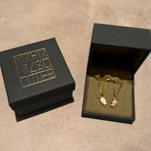 Halsband Maria Nilsdotter ”You & Me Necklace” - Två guldiga halsband från Maria Nilsdotter med matchande berlocker i form av ett delat hjärta. ”You & Me Necklace” på hemsidan, nypris 4995 kr. Orginalförpackning/box tillkommer! Bra skick!