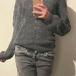 grå stickad tröja Angelology - Säljer en mörkgrå stickad tröja från Angelology i storlek S. Tröjan har ett snyggt strukturerat mönster och ribbade muddar vid ärmslut och midja. 