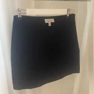 Svart Kort Kjol från & Other Stories storlek 38 - Enkel och stilren svart kortkjol från & Other Stories. Kjolen har rak passform och är perfekt för dig som gillar minimalistisk stil. Tillverkad i ett slätt material som ger en clean look. Passar till allt och är lätt att matcha med olika toppar.