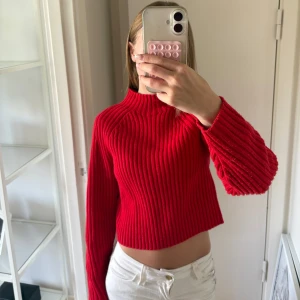 Röd stickad tröja - Säljer en röd stickad tröja med ribbad struktur och lång ärm. Tröjan har en högre halsringning och en loose passform som ger en chill vibe. Perfekt att styla med höga eller låga jeans eller kjol för en trendig look. Storlek xxs!🥰